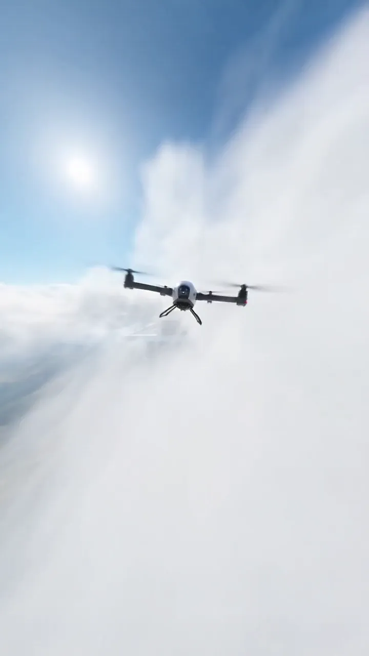 Quadcopter drone flying above a sea of clouds under a blue sky