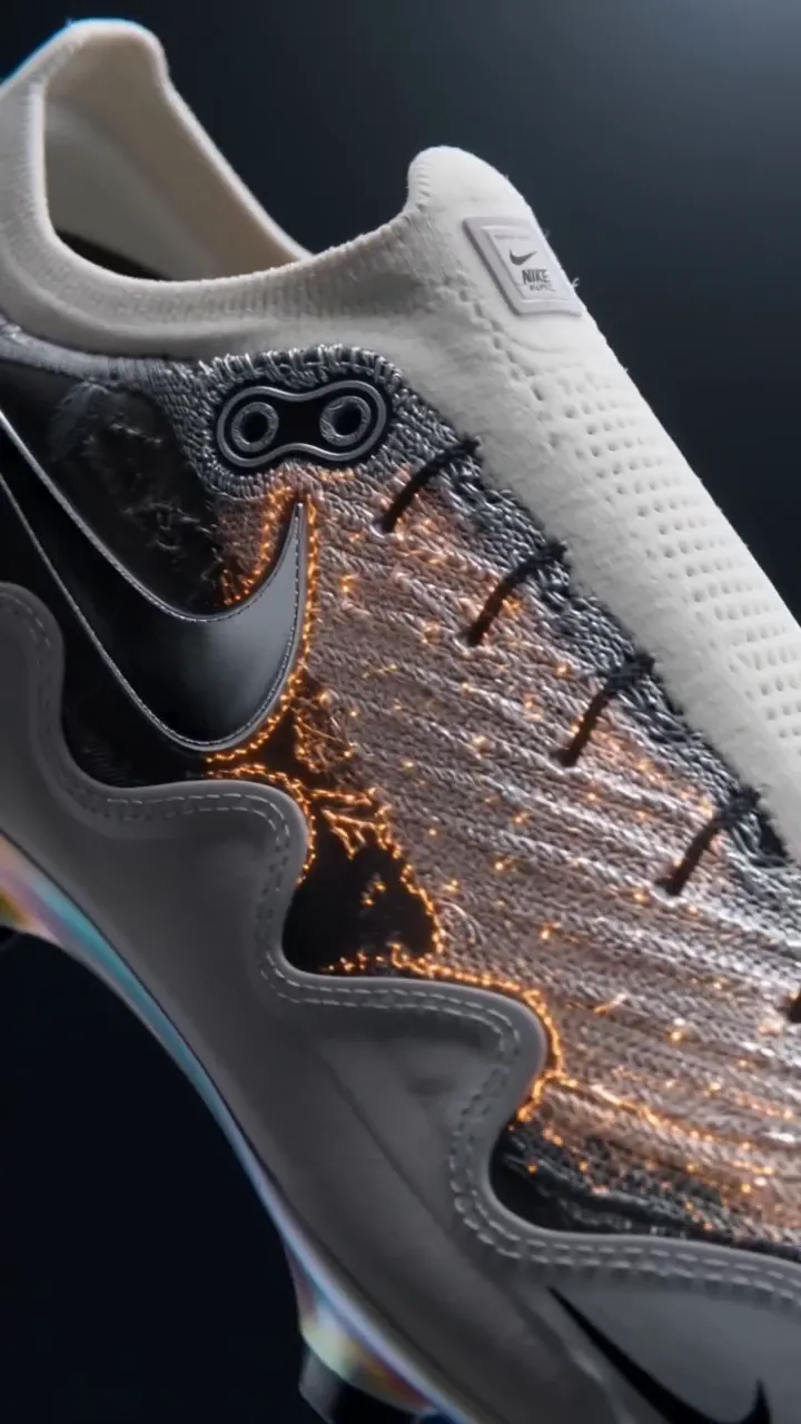 Extreme close-up of a knitted football boot with molten orange detailing on a dark studio background